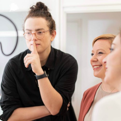 Drei Personen betrachten ein Kameradisplay während einer Videoaufnahme für einen Imagefilm.